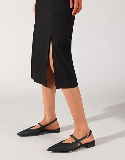 Person wearing a black dress with a slit and black shoes on a white background