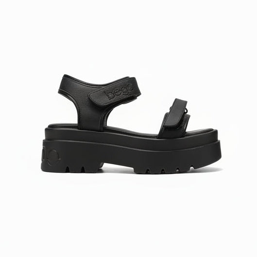 A black platform sandal with double straps and a thick lug sole, featuring the brand name 'bego' embossed on the ankle strap, shown against a plain white background.