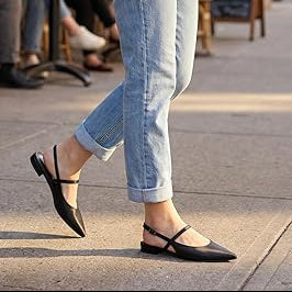 Woman walking on a city street with people sitting at outdoor tables in the background